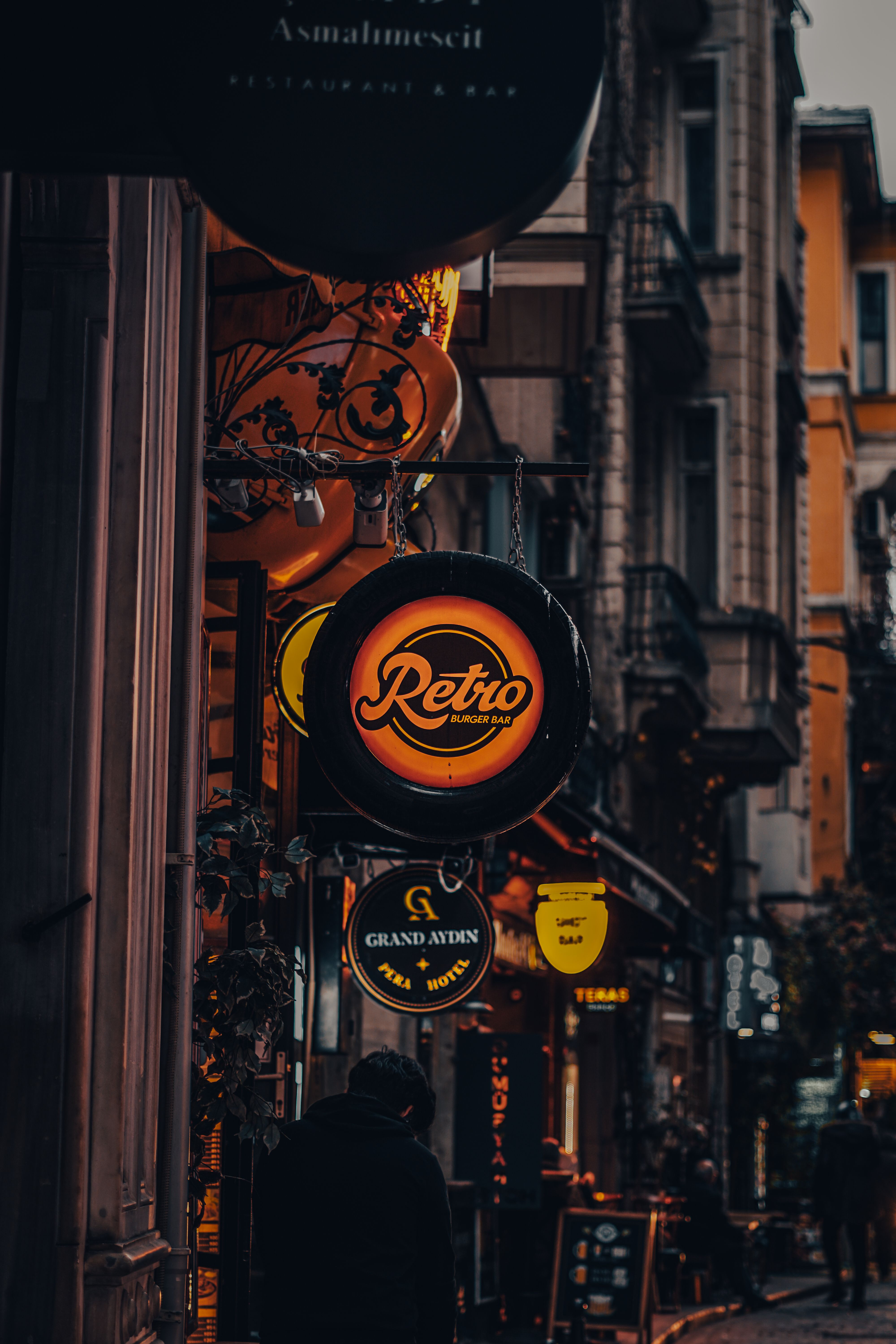 Lively European urban street illuminated by bright neon bar signs at night