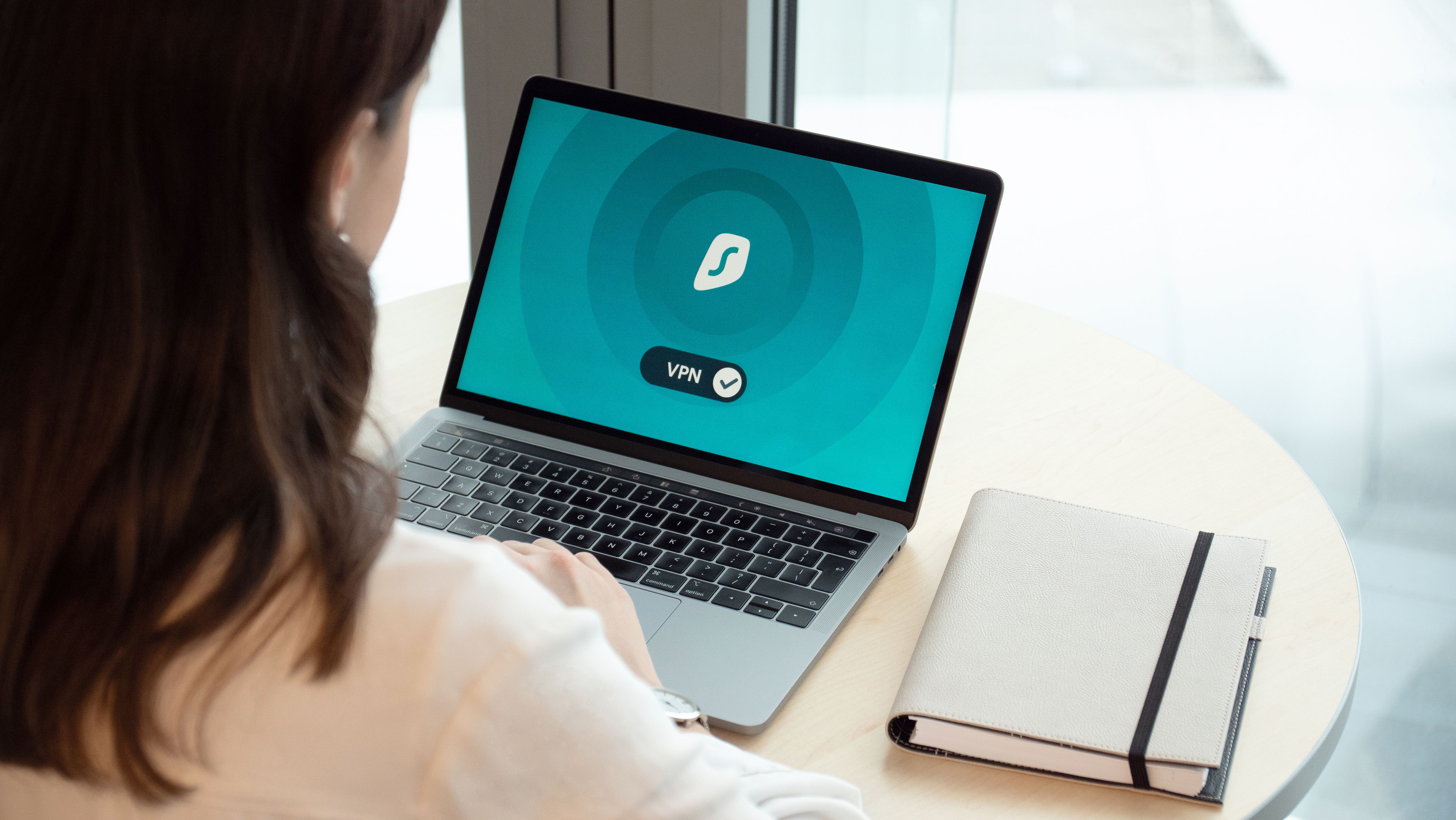 Woman working on a laptop with a VPN security icon for secure cross-border access
