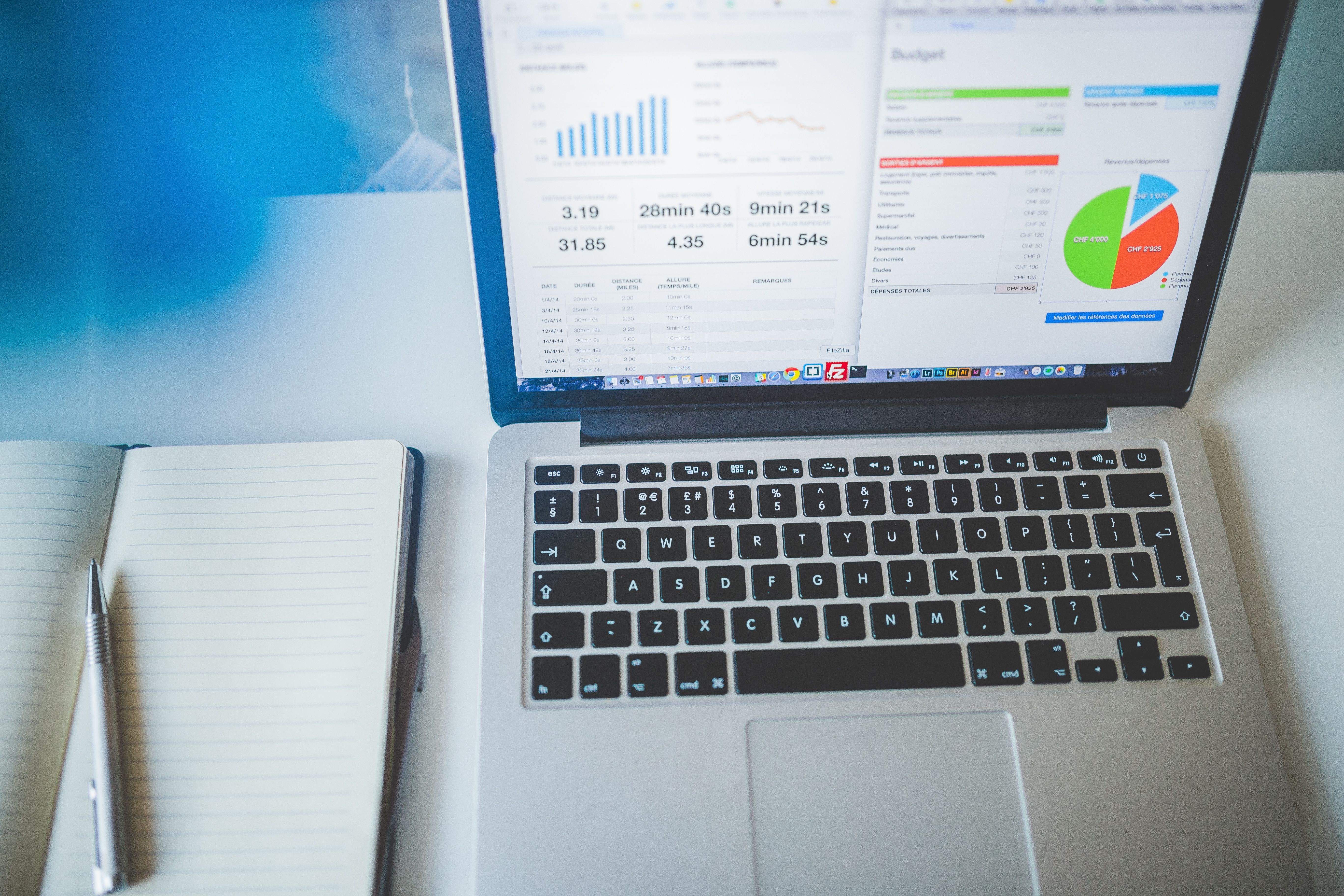 Laptop displaying business charts beside a notebook, representing digital revenue tracking and financial analysis.