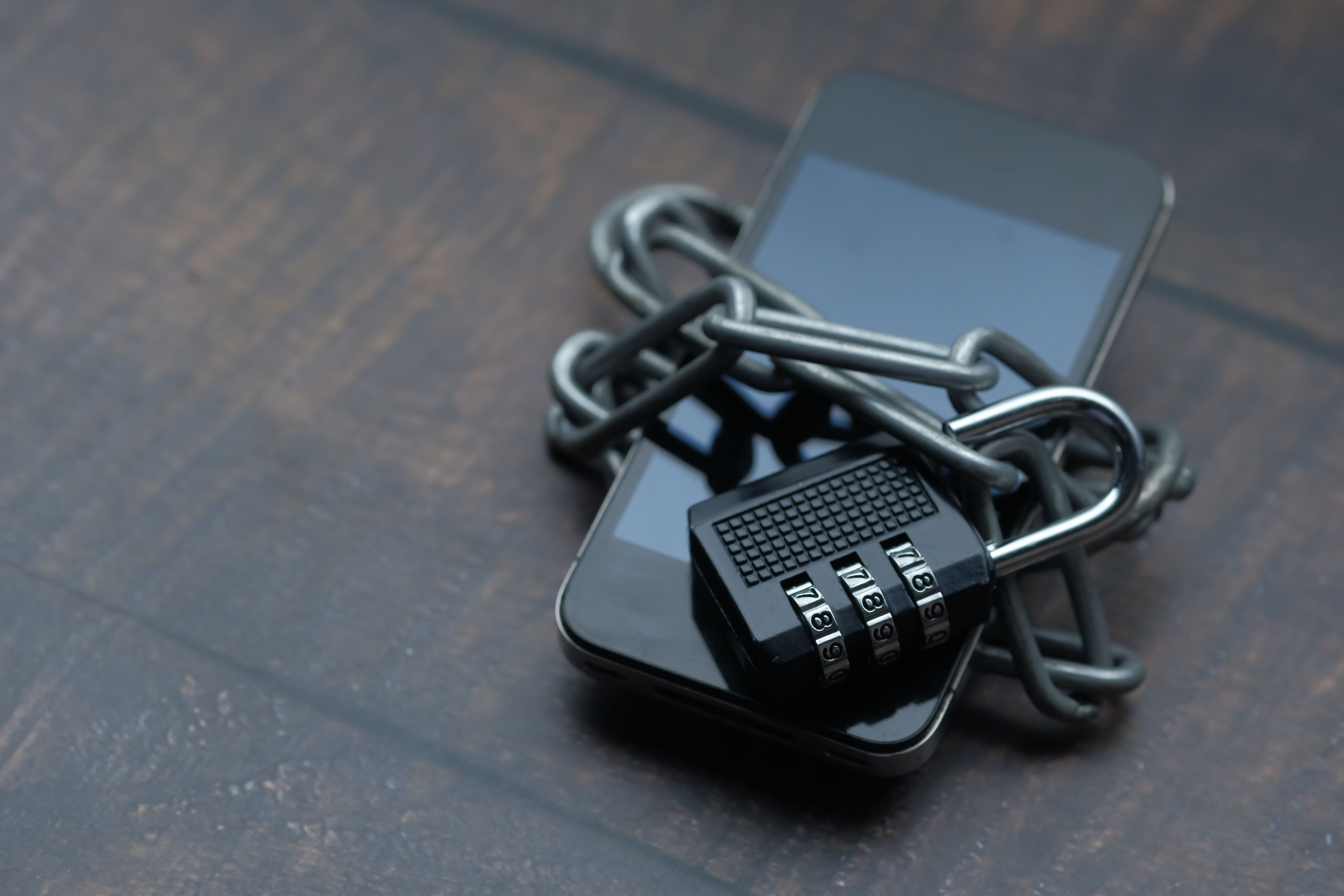 Smartphone wrapped in a chain with a padlock, symbolizing secure messaging and protection against account abuse.