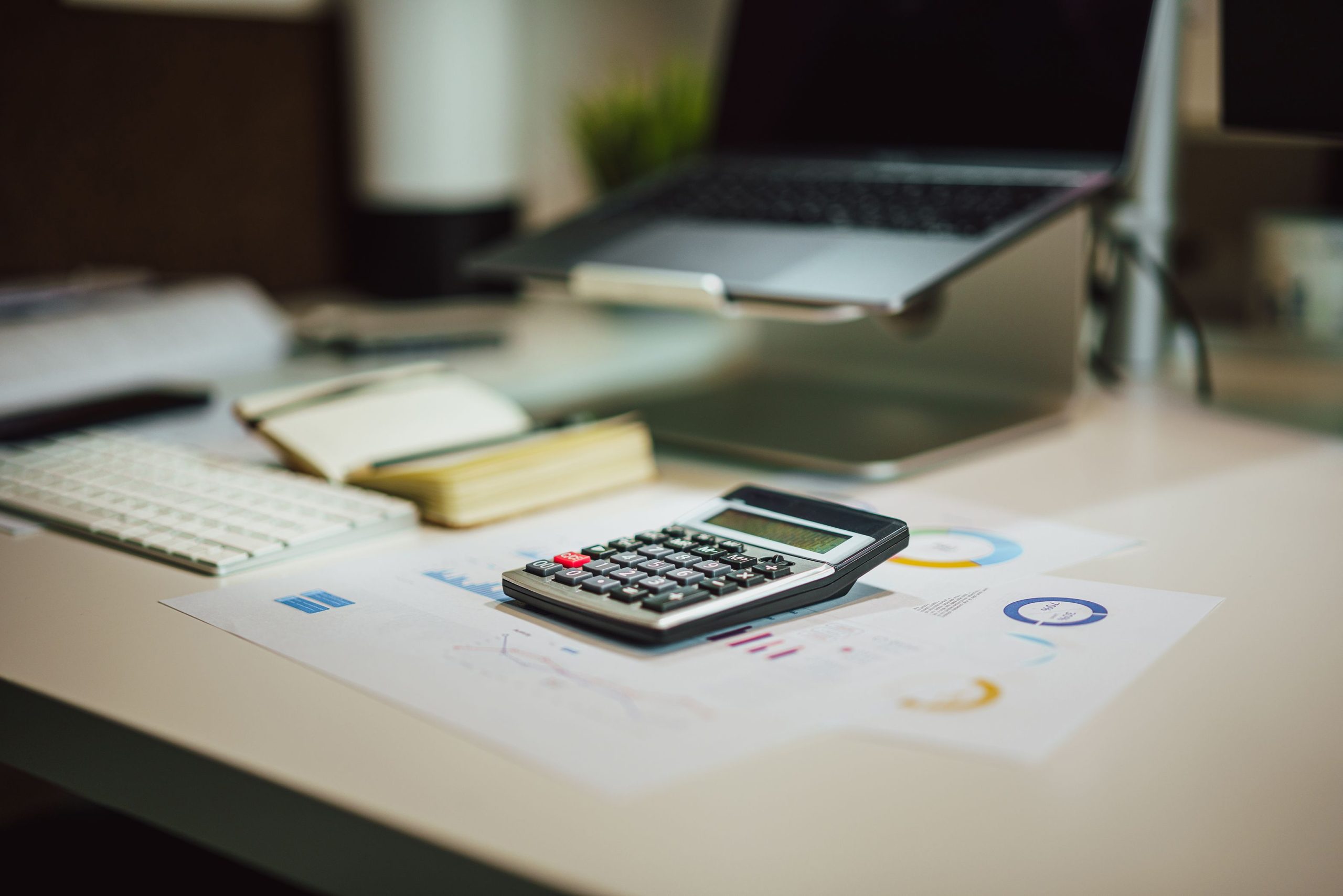 Small-business finance workspace with laptop, calculator, and accounting documents for budgeting and cash-flow planning.