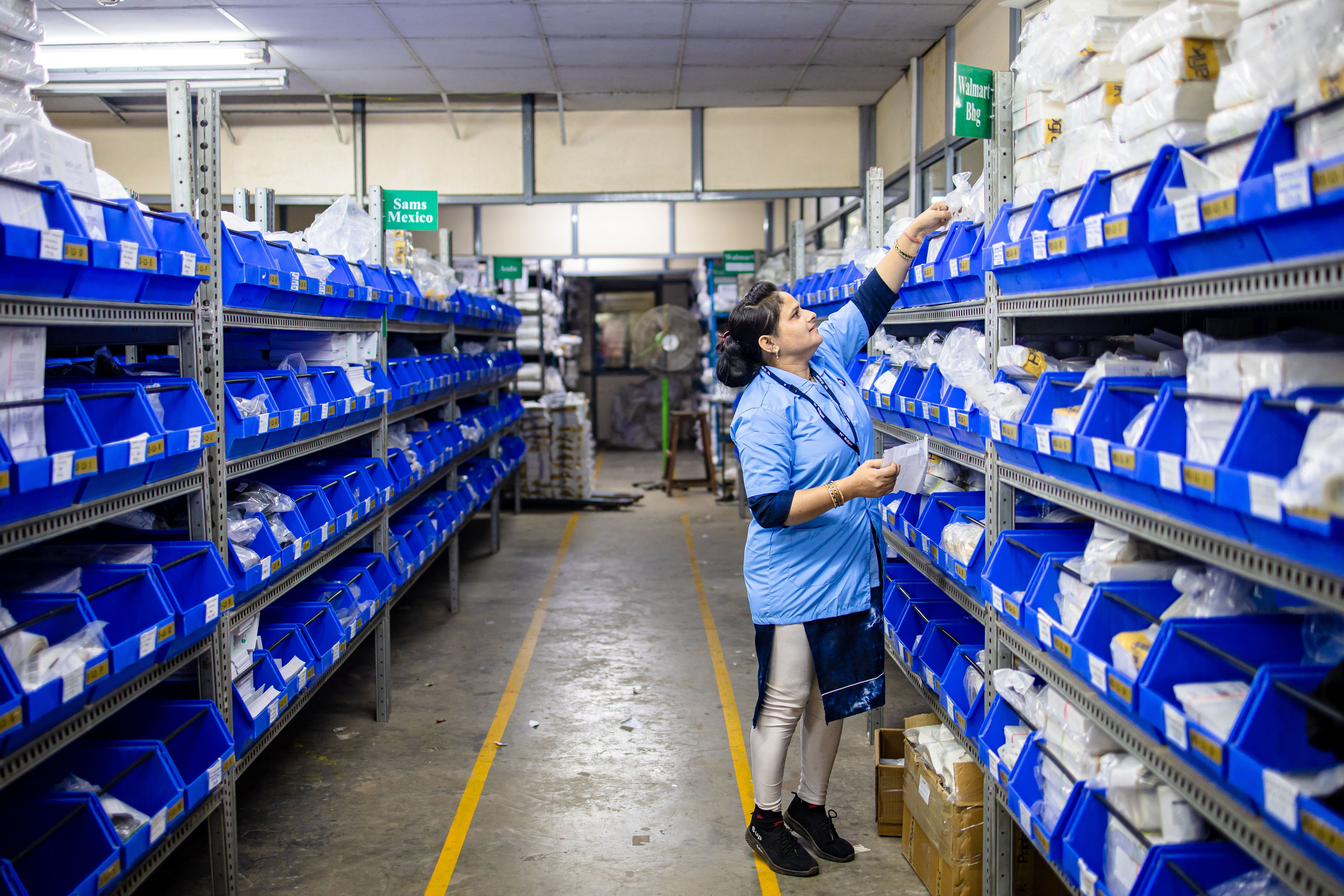 Warehouse worker organizing inventory in labeled bins, illustrating operational supply chain visibility.